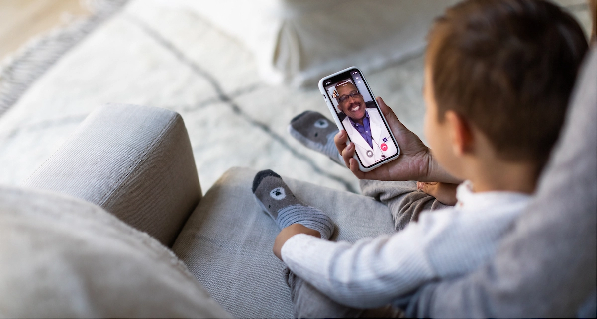 Mom with child talking to a doctor on Doctor On Demand app.