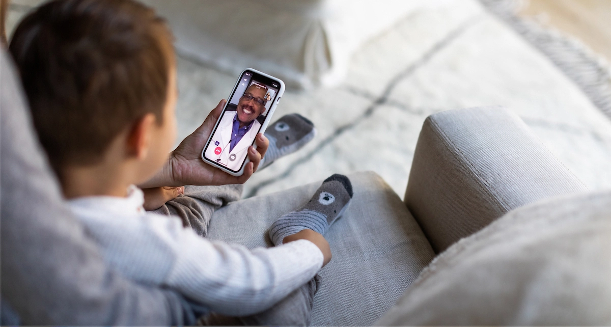 Mom with child talking to a doctor on Doctor On Demand app.